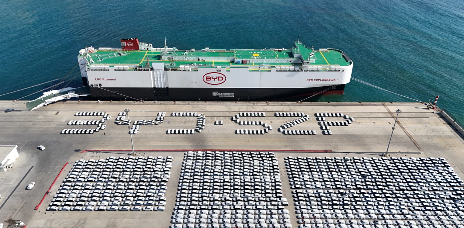 A massive Roll-on/Roll-off (RoRo) shipping vessel loading electric vehicles at a port