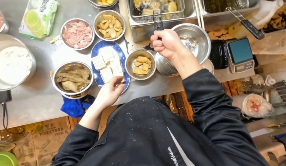 A contract worker wearing head and wrist cameras records a cooking task in a home kitchen for robot training data
