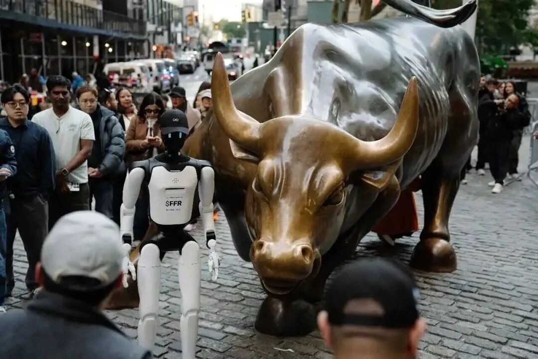 An FFR branded humanoid robot standing in front of the Charging Bull statue in New York
